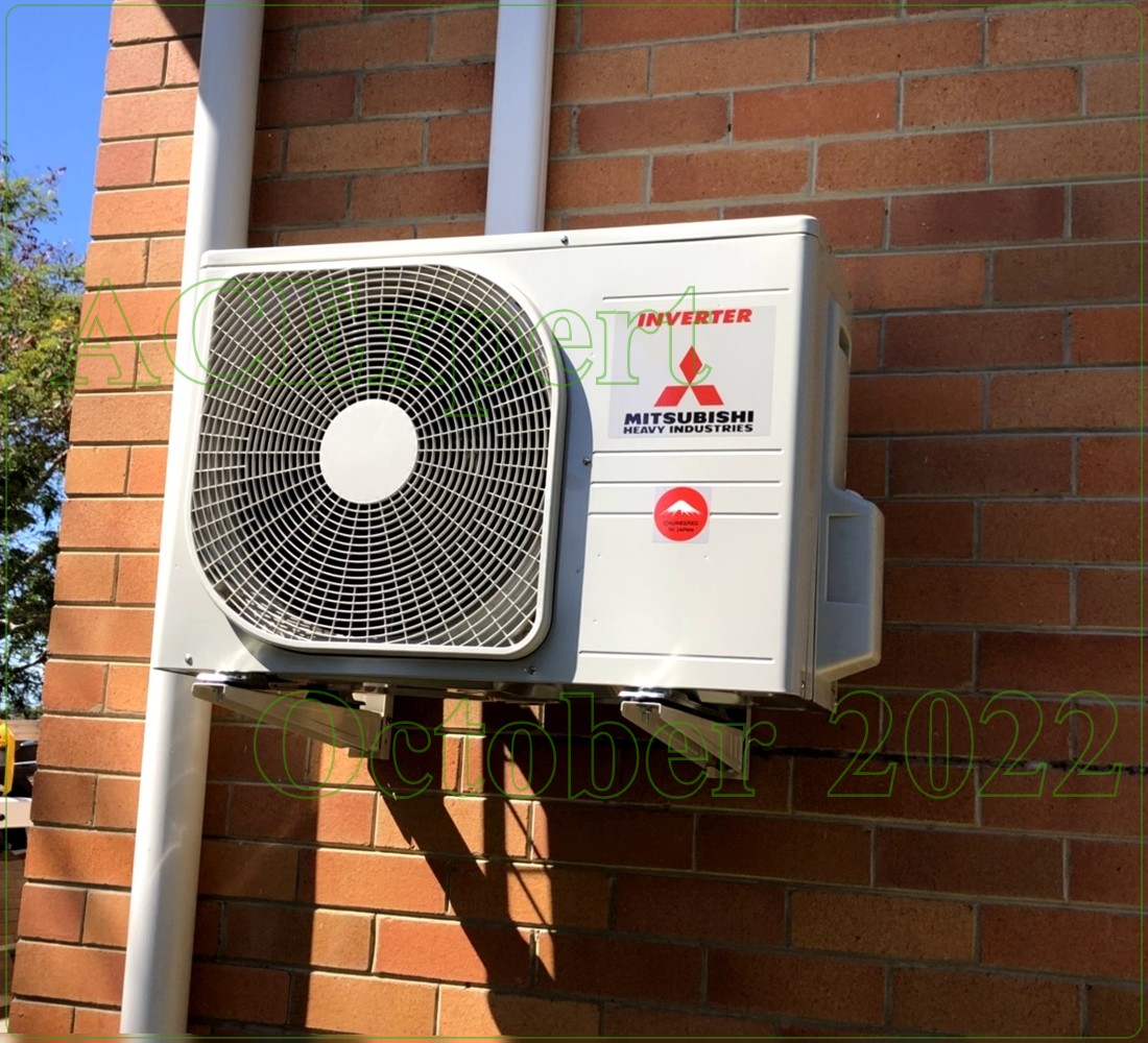 Outdoor unit on a brick wall with clear winter servicing access and safety signage